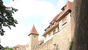Un bâtiment historique en pierre, doté d’une tour et entouré de verdure.