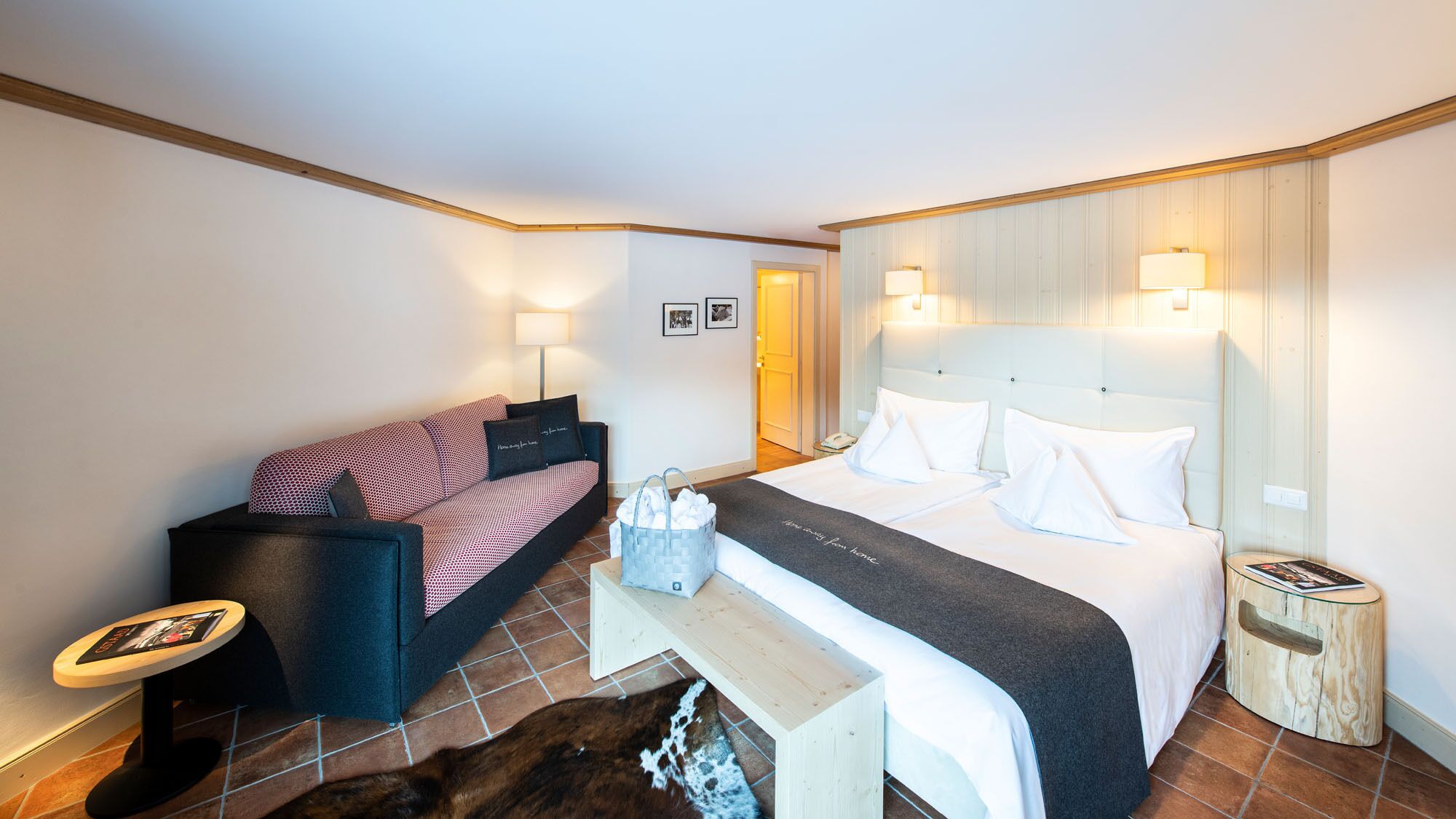 A hotel room with a bed, a sofa, a small table, and a nightstand.