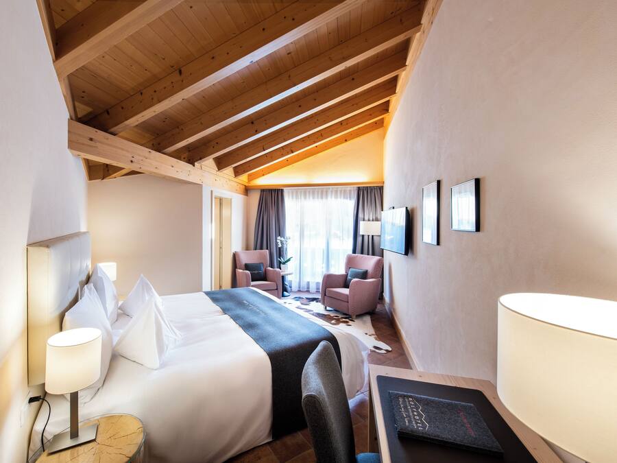Habitació d'hotel amb un llit gran, dues cadires, un escriptori i una làmpada.