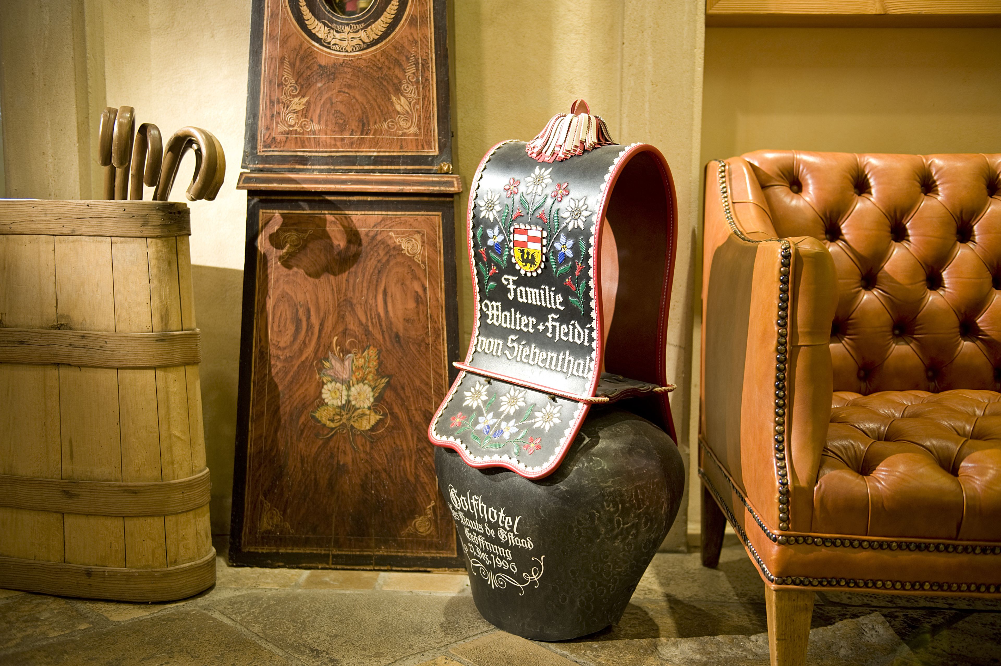 A traditional wooden barrel, a decorative wooden cabinet, and a leather armchair in a room with stone flooring.