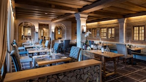 A restaurant with wooden tables and benches, stone walls, and arched doorways. - Golfhotel Les Hauts de Gstaad & SPA (Saanen)