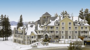 A multi-story building with a symmetrical facade, balconies, and a snow-covered landscape.