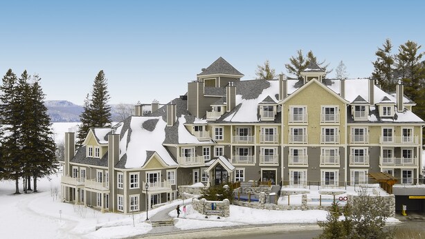 A multi-story building with a symmetrical facade, balconies, and a snow-covered landscape.