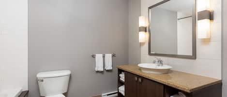Un baño moderno con inodoro, lavamanos y espejo.