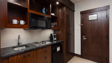 Una cocina con armarios de madera, microondas, cafetera y lavavajillas.