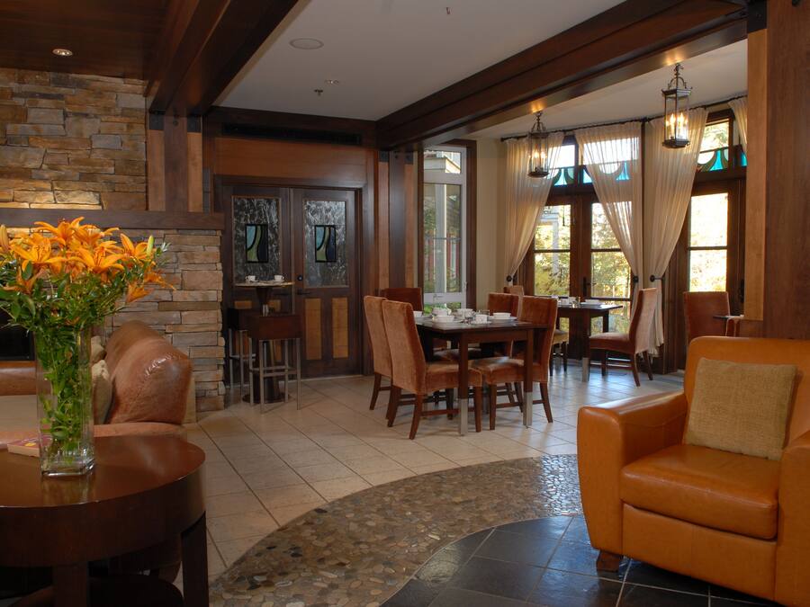 A spacious living area with a stone wall, a fireplace, a dining table with chairs, and a comfortable orange armchair.