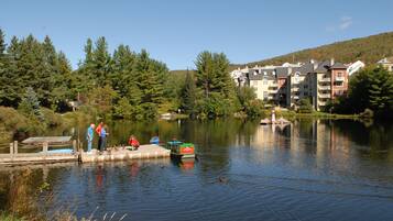 A lakeside view with a dock, people, and buildings in the background.
