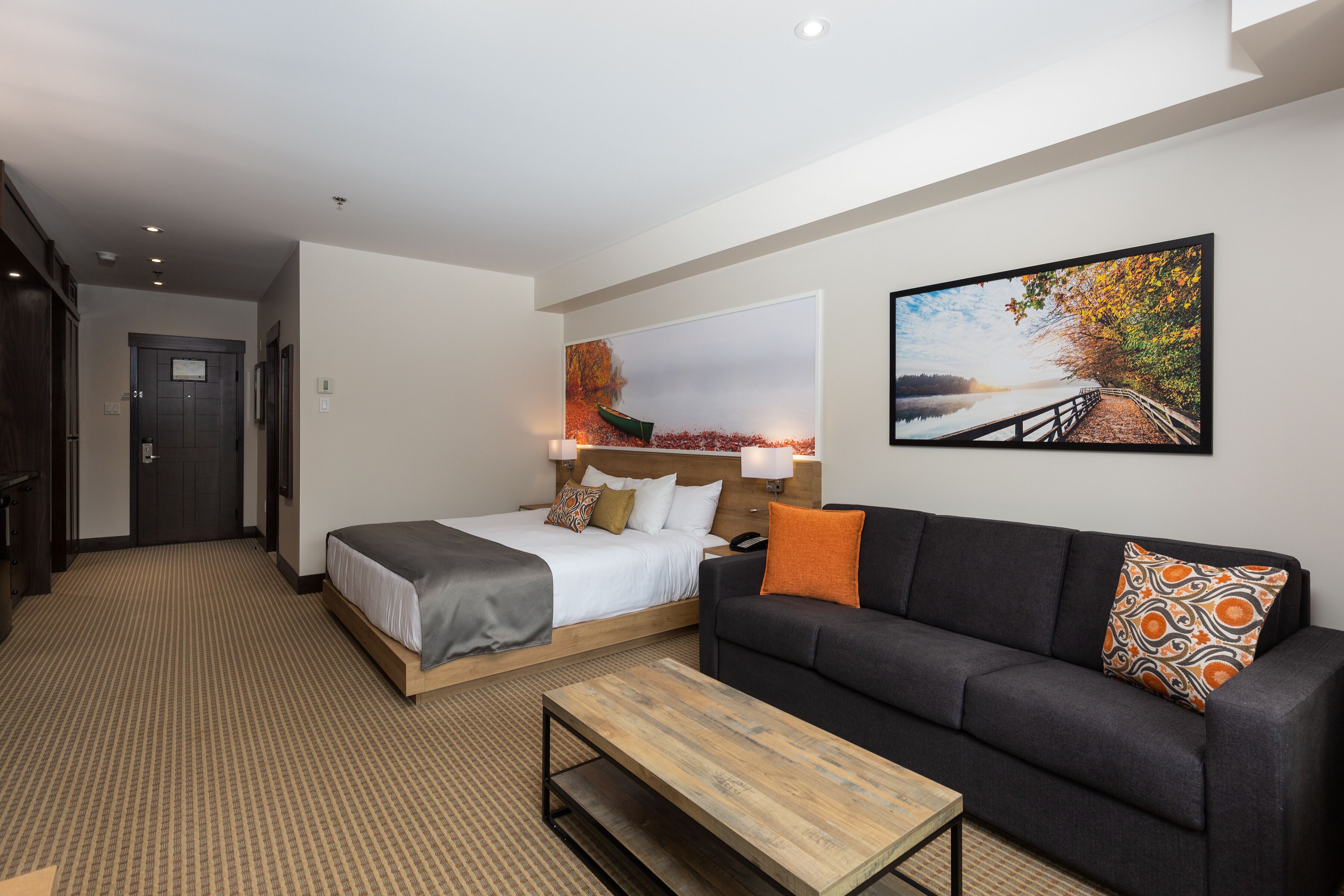 Une chambre d’hôtel avec un lit, un canapé, une table basse et deux tableaux accrochés au mur.