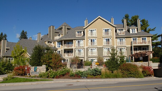 A multi-story residential building with a central courtyard, balconies, and a well-maintained lawn.