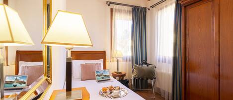 A hotel room with a wooden bed, a laptop, a tray with breakfast, and a large mirror.