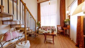 A cozy living room with a wooden staircase, a sofa, a dining table, and a coffee table. - Hotel Venice Resort Airport (Mestre)