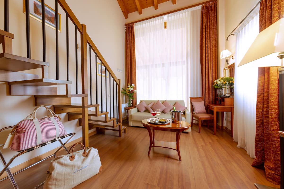 Ein gemütliches Wohnzimmer mit einer Holztreppe, einem Sofa, einem Esstisch und einem Couchtisch.