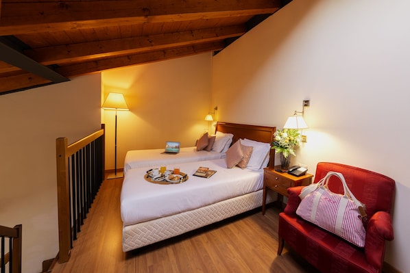 A hotel room with a wooden ceiling, two beds with white bedding, a red armchair, and bedside lamps.