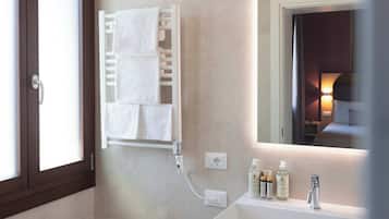 Une salle de bain moderne équipée d’un bidet, d’un lavabo avec des articles de toilette, d’un porte-serviettes et d’un miroir.