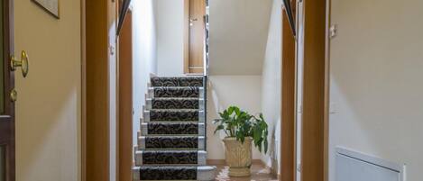 Un pasillo con alfombra estampada que conduce a una escalera.