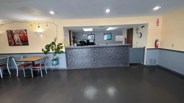 A reception area with a counter, chairs, and a potted plant. - Residential Suites Warrensburg by Hotel O US 50 (Knob Noster)