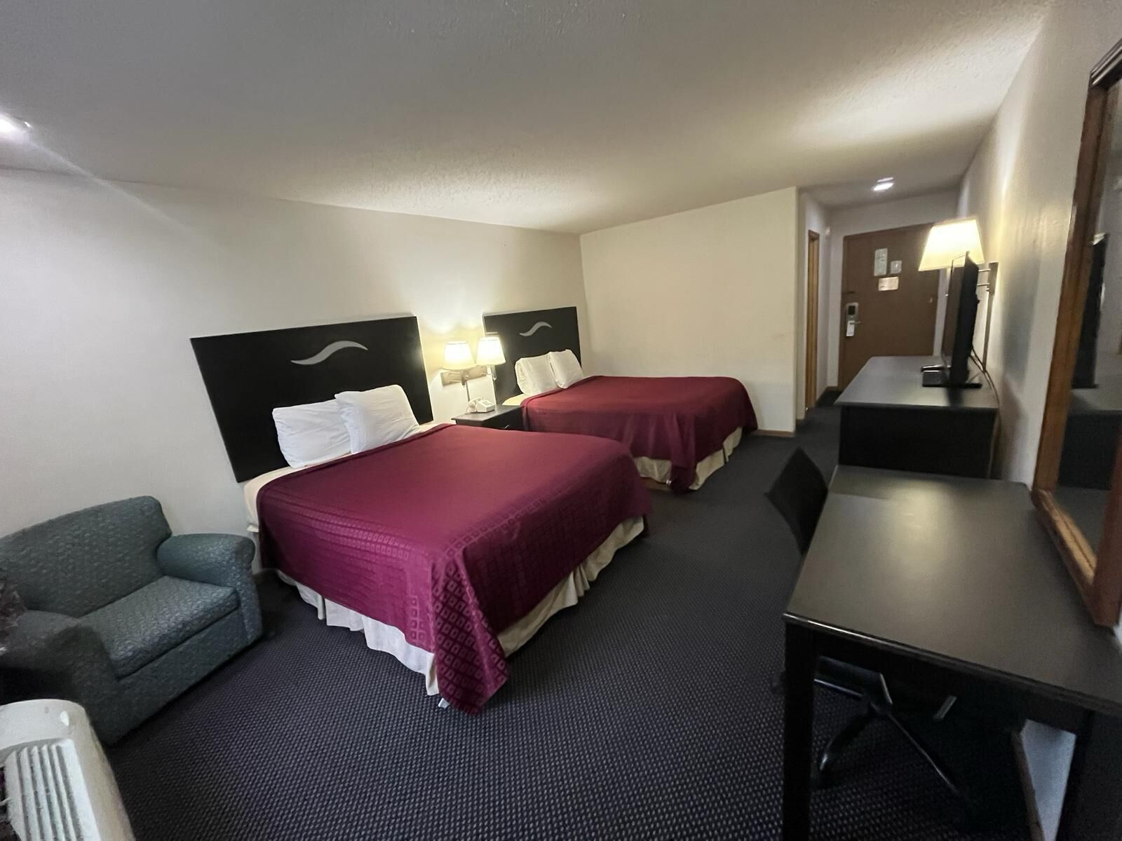Een hotelkamer met twee bedden, een bureau, een stoel en een bank.