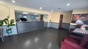 A reception area with a counter, seating, and a large painting on the wall. - Residential Suites Warrensburg by Hotel O US 50 (Knob Noster)