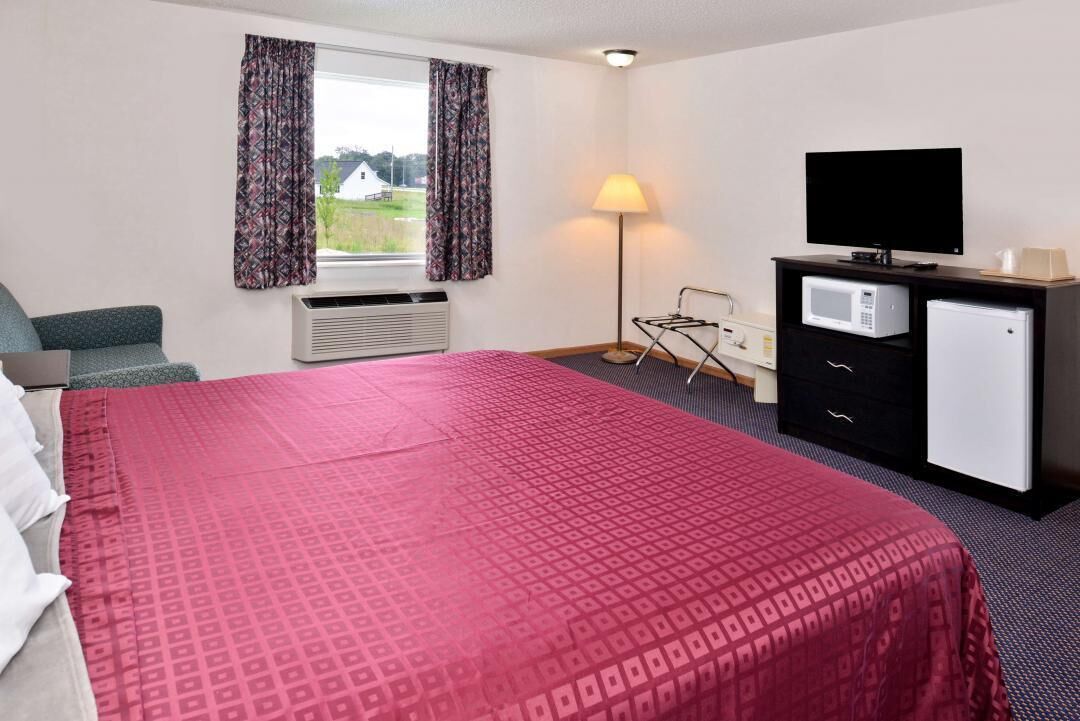 A hotel room with a large bed, a flat-screen TV, a microwave, and a small refrigerator.