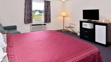 A hotel room with a large bed, a flat-screen TV, a microwave, and a small refrigerator.