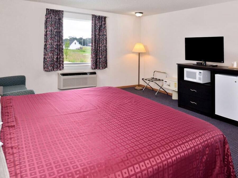 A hotel room with a large bed, a flat-screen TV, a microwave, and a small refrigerator.