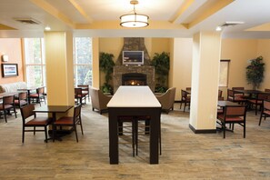 A restaurant with a stone fireplace, multiple tables, and chairs.