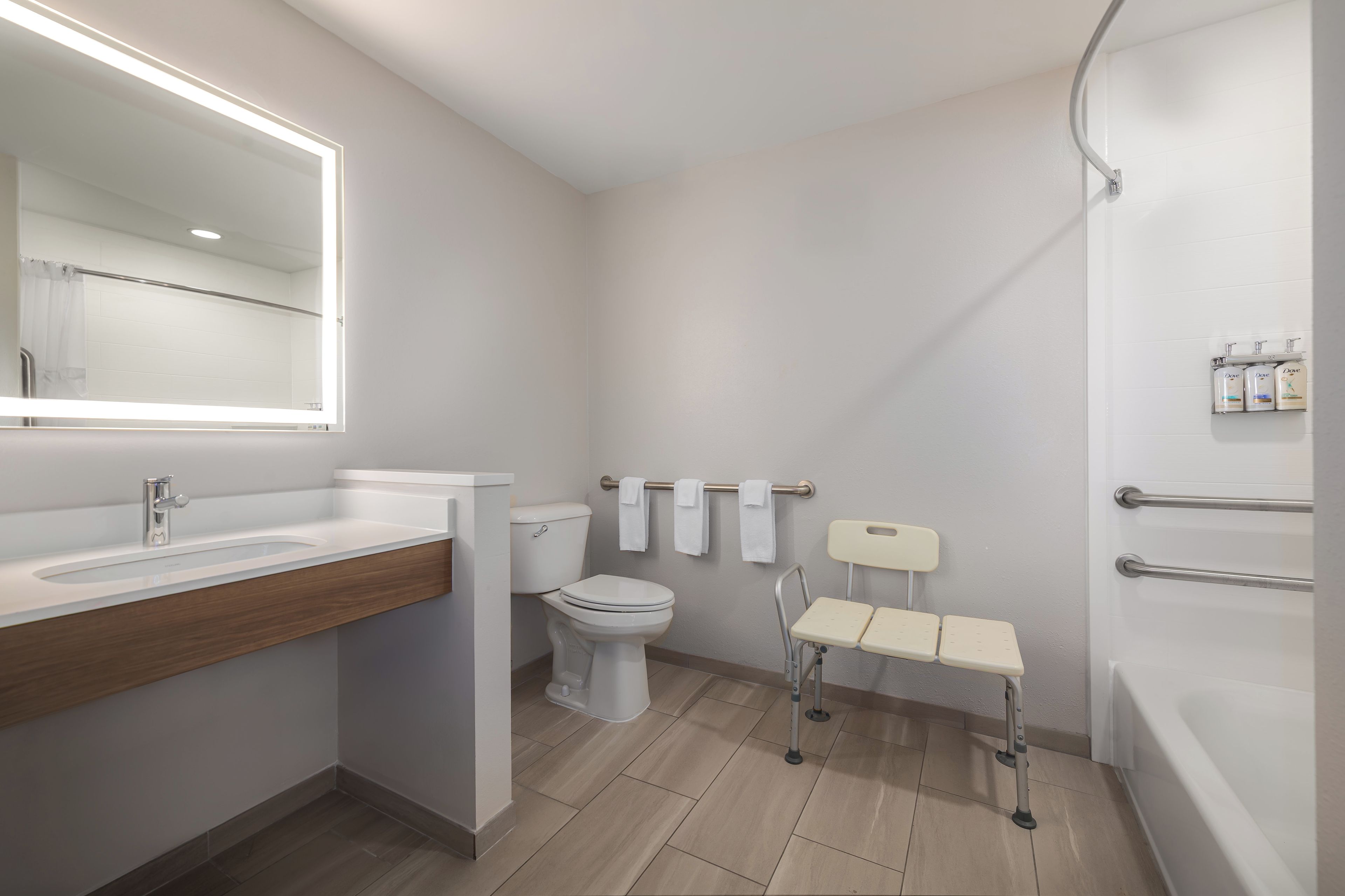 A modern bathroom with a large mirror, a toilet, a sink, and a shower.