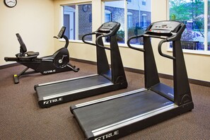 Une salle de sport équipée de tapis de course et d’un appareil elliptique.
