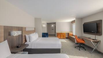 A hotel room with two beds, a desk, a TV, and a bathroom in the background.