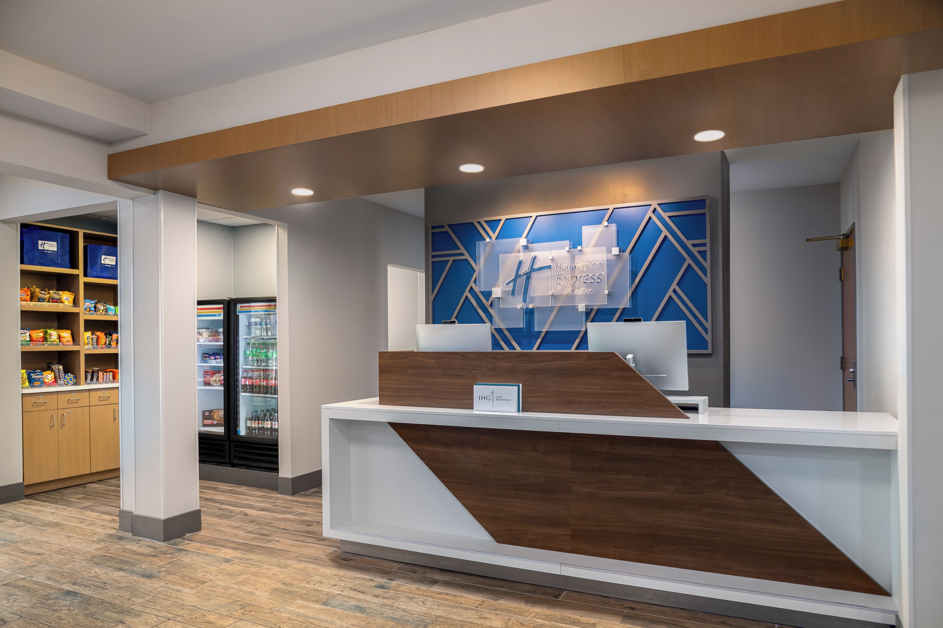 Una recepción de diseño moderno, un adorno mural geométrico azul y un refrigerador lleno de bebidas.