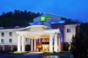 En byggnad som inrymmer ett Holiday Inn Express & Suites-hotell, med en ingång som är skyddad av ett tak och en fasad av tegel.
