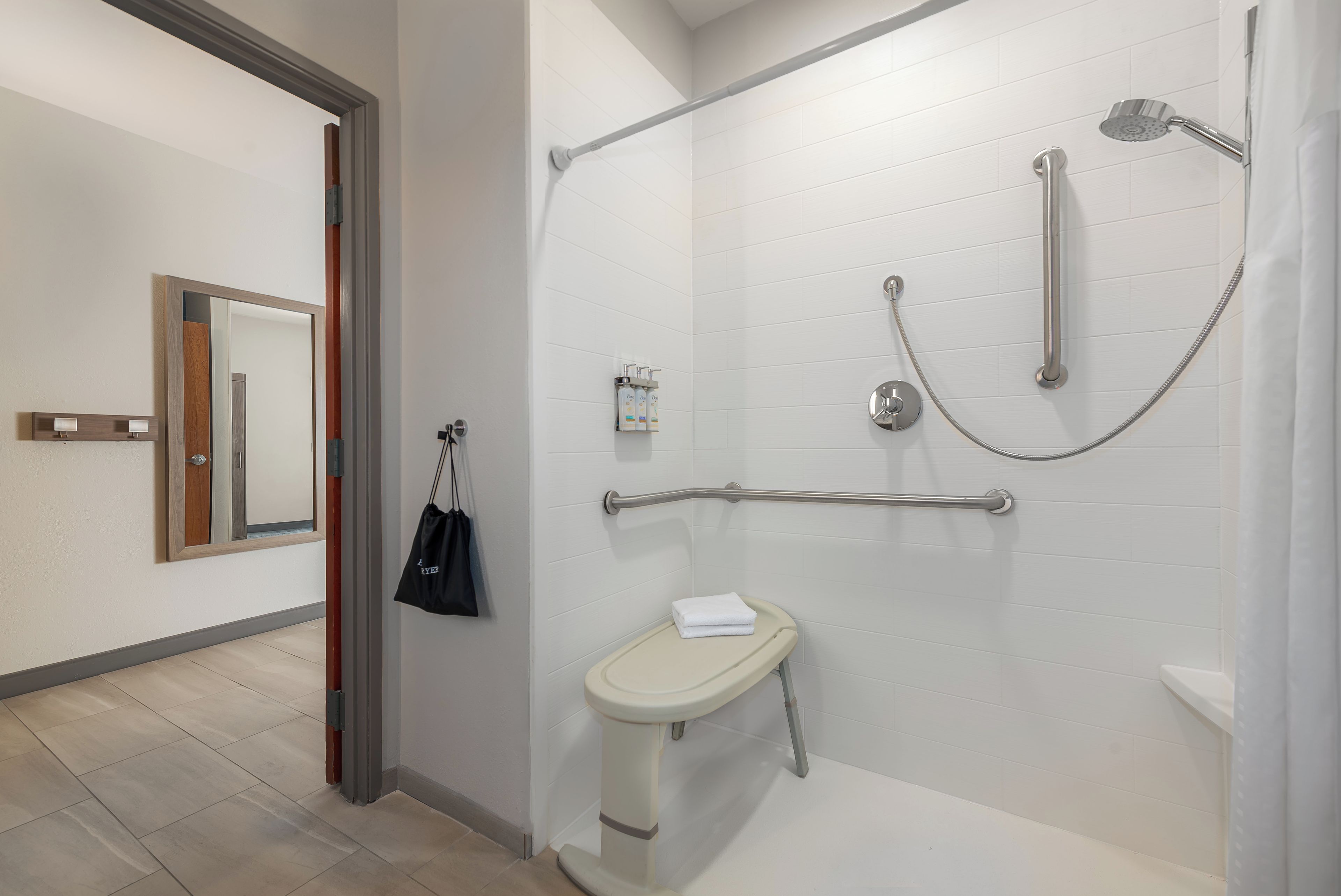 A modern bathroom with a walk-in shower, grab bars, and a toilet.