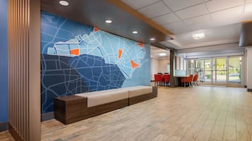 A reception area with a large wall map, a seating bench, and a dining area with red chairs.