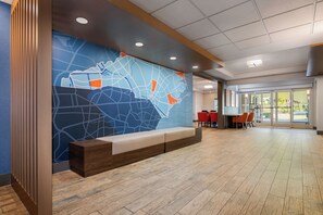 A reception area with a large wall map, a seating bench, and a dining area with red chairs.