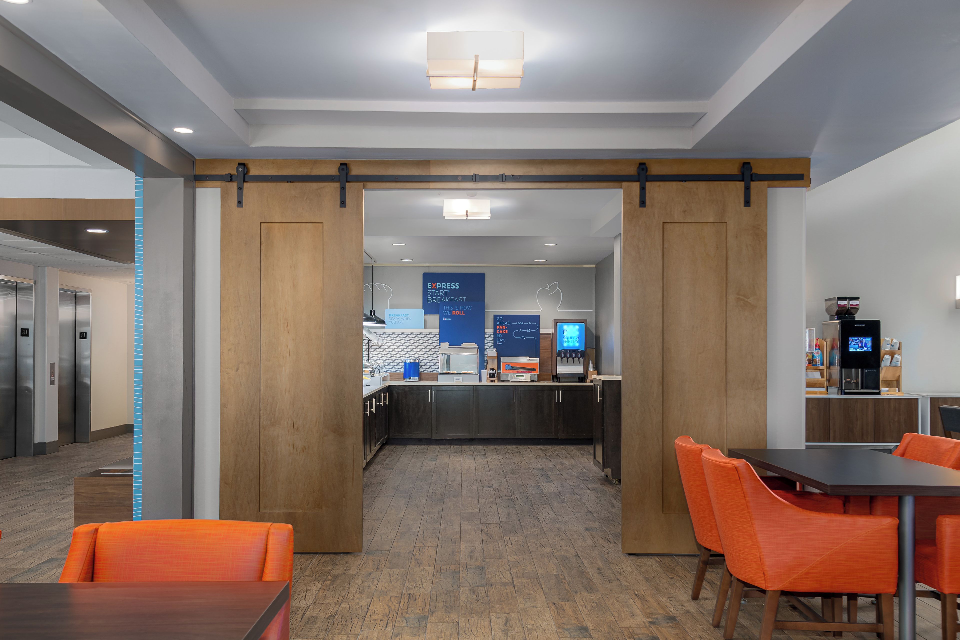 Un hall d’hôtel moderne avec un comptoir d’accueil, une machine à café et un espace salon.