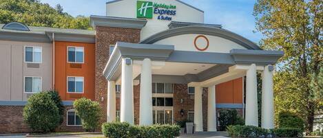 A Holiday Inn Express & Suites hotel with a brick facade, large entrance, and a parking lot.