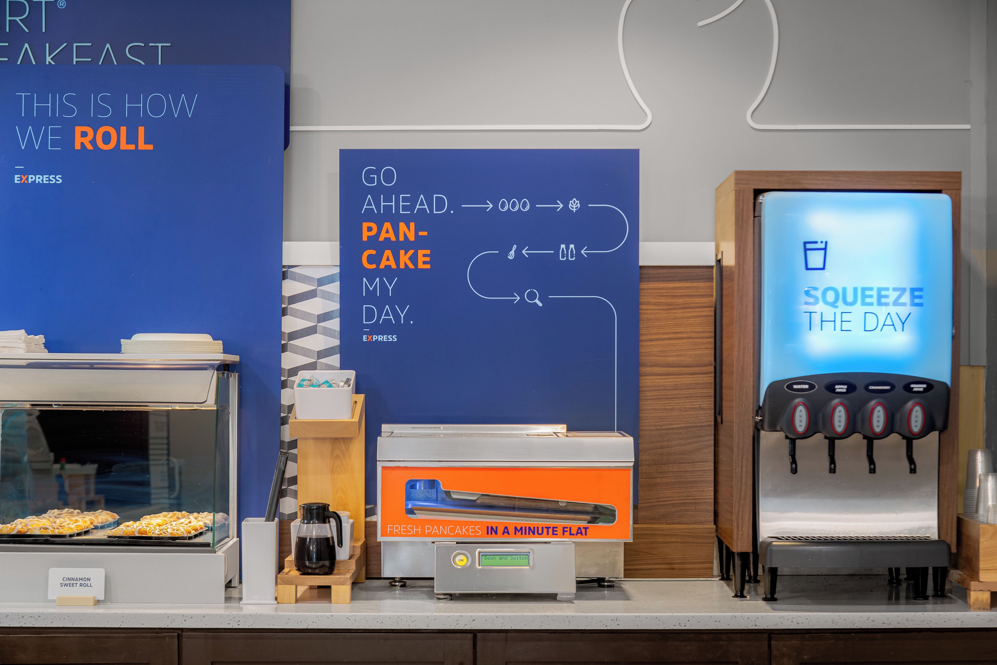 A breakfast area with a menu board, a pancake-making machine, and a beverage dispenser.