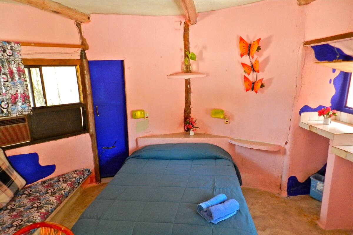 A bedroom with a bed, a chair, a desk, and a window.