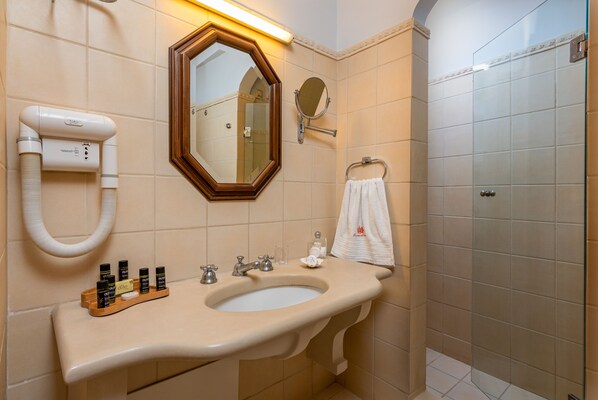 Un baño con un lavabo color beige, un espejo, un perchero para toallas y una cabina de ducha de vidrio.