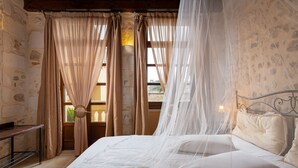 Een slaapkamer met een bed, gordijnen, een nachtkastje en een raam met uitzicht.