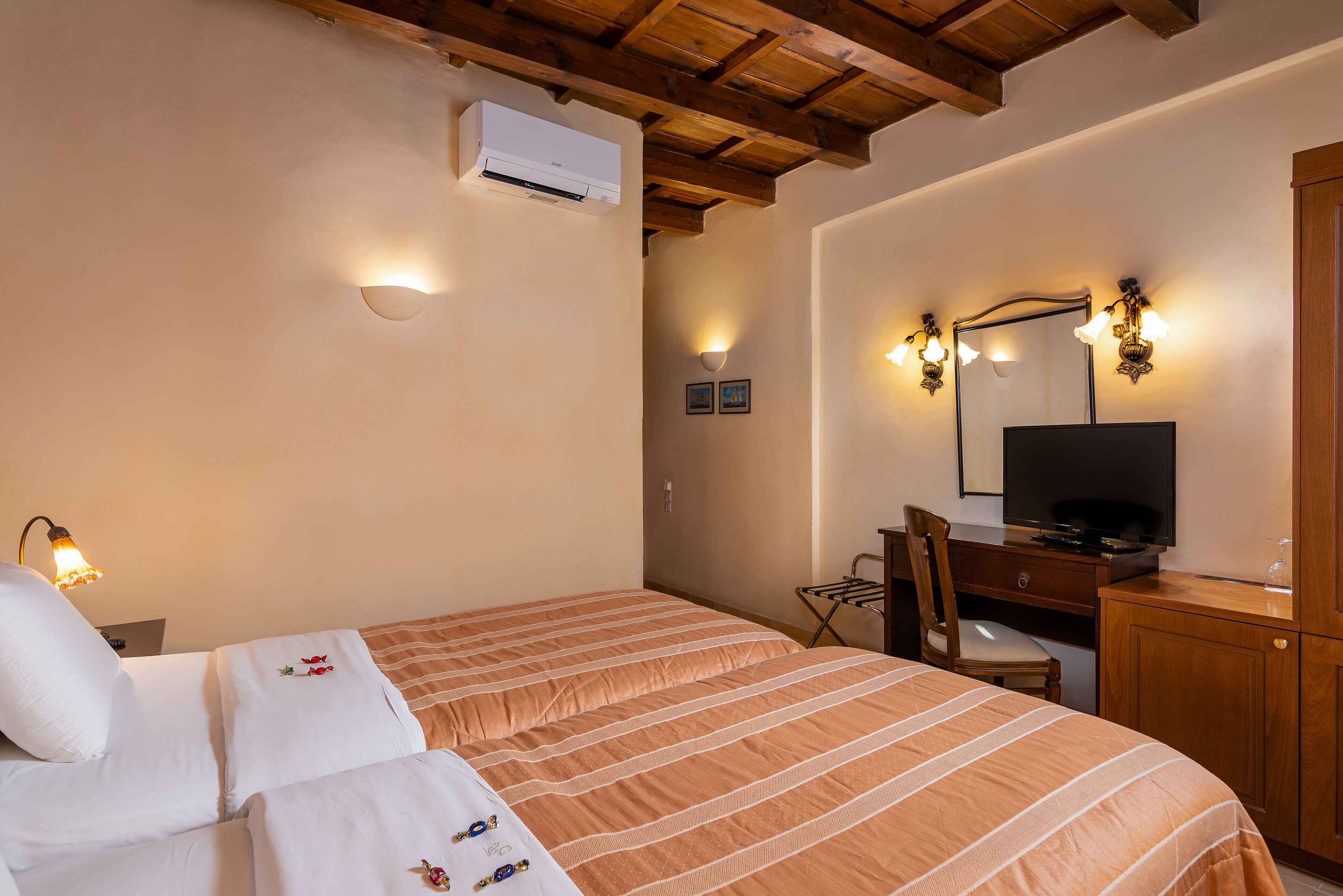 Habitación de hotel con cama, escritorio con televisor, una silla y armario de madera.