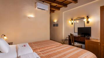 Habitación de hotel con cama, escritorio con televisor, una silla y armario de madera.