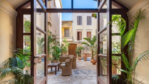 A courtyard with wicker furniture, potted plants, and a cobblestone floor. - Palazzino Di Corina (Rethymno)
