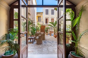 A courtyard with wicker furniture, potted plants, and a cobblestone floor. - Palazzino Di Corina (Rethymno)