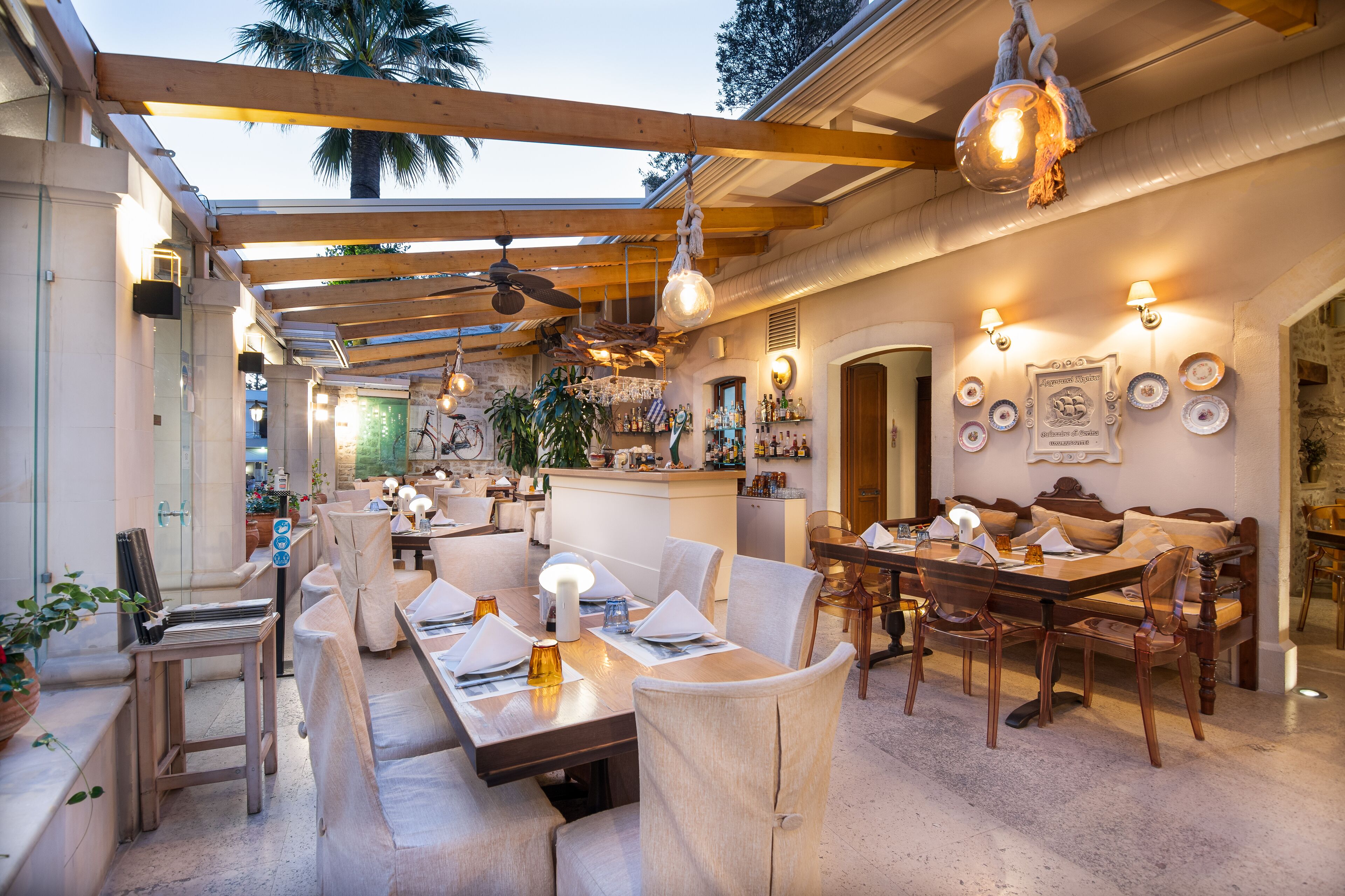 Un restaurante con vigas de madera, luces colgantes y una zona de bar.