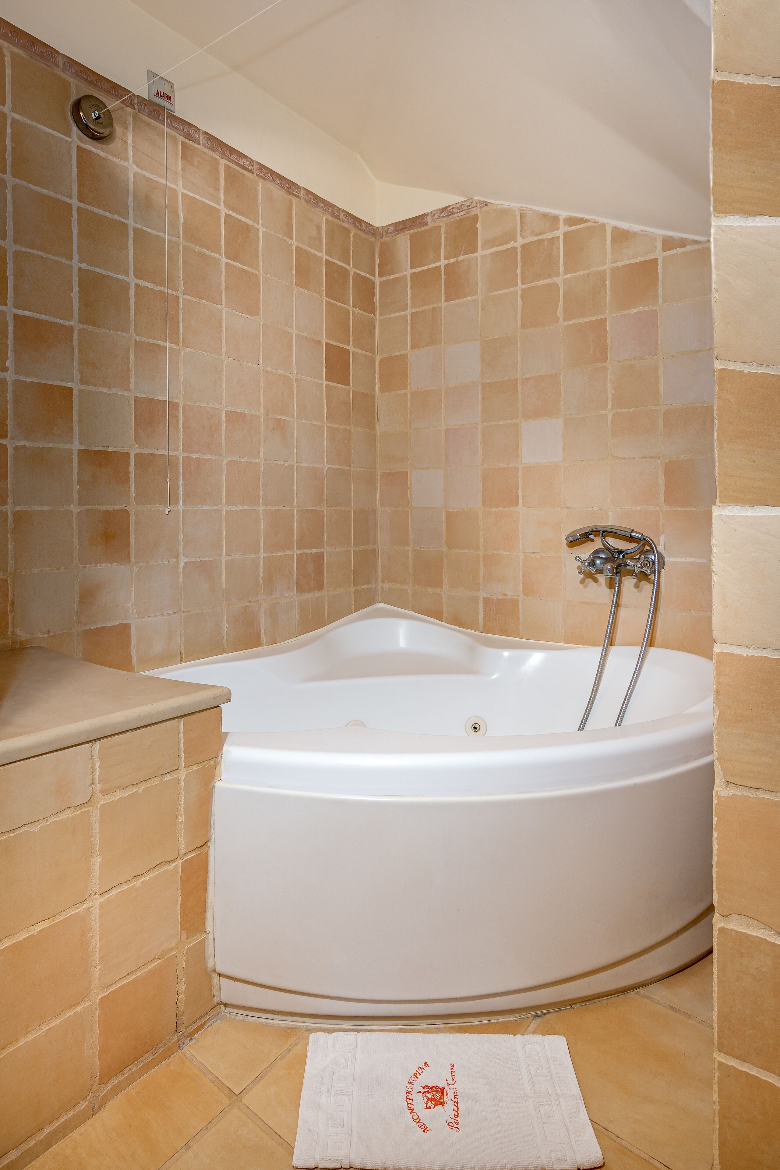 A bathroom with a freestanding bathtub, a towel, and a wall-mounted alarm.