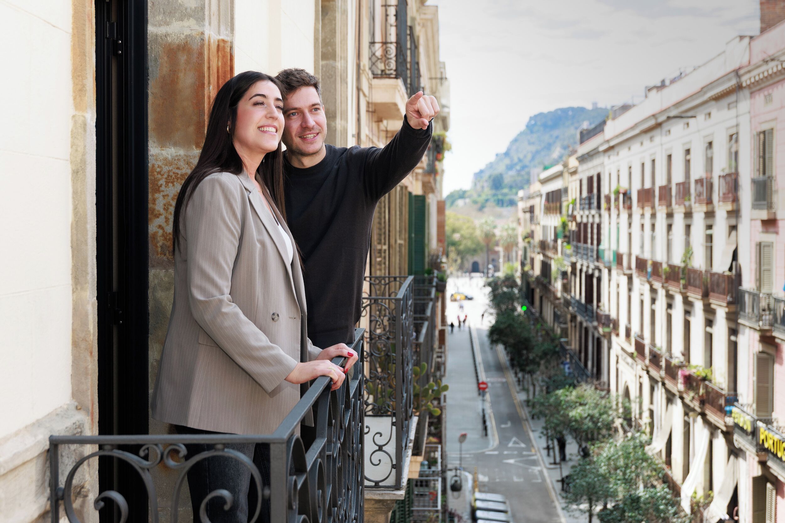 Una pareja parada en un balcón con vista a una calle de la ciudad.