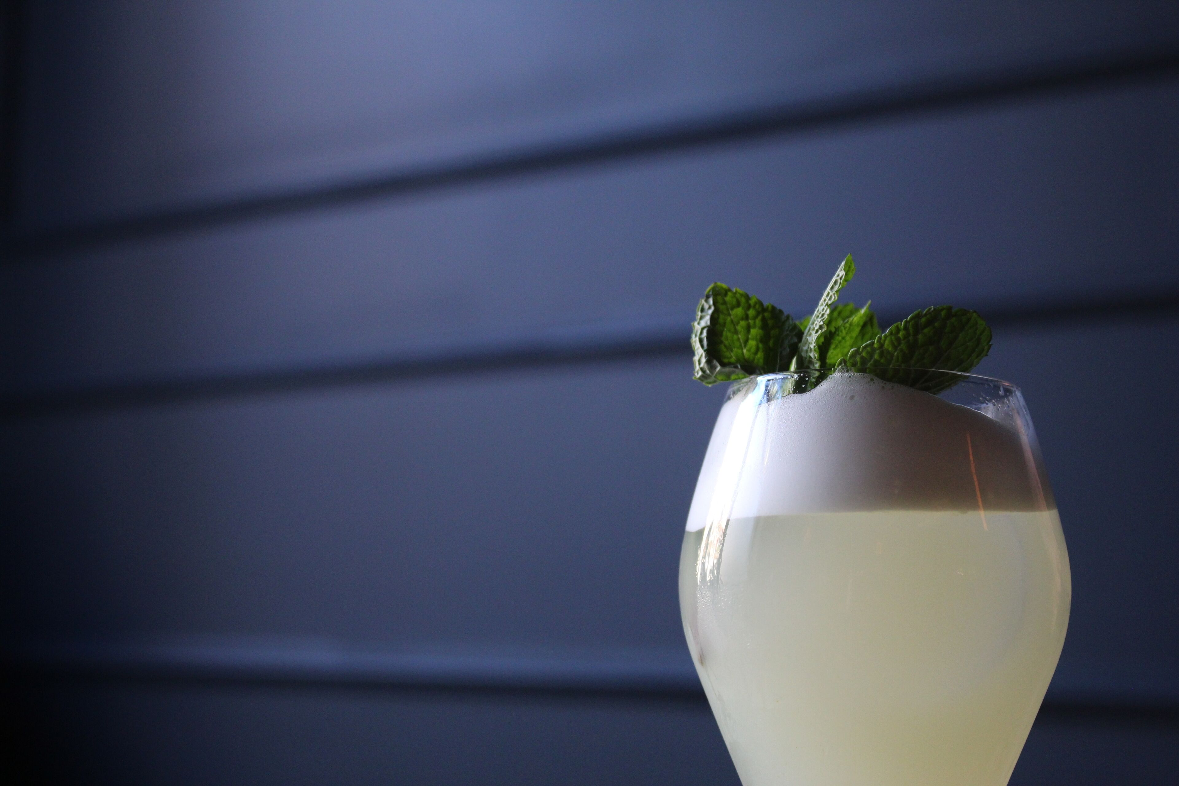 Un vaso con líquido transparente y hojas de menta encima.