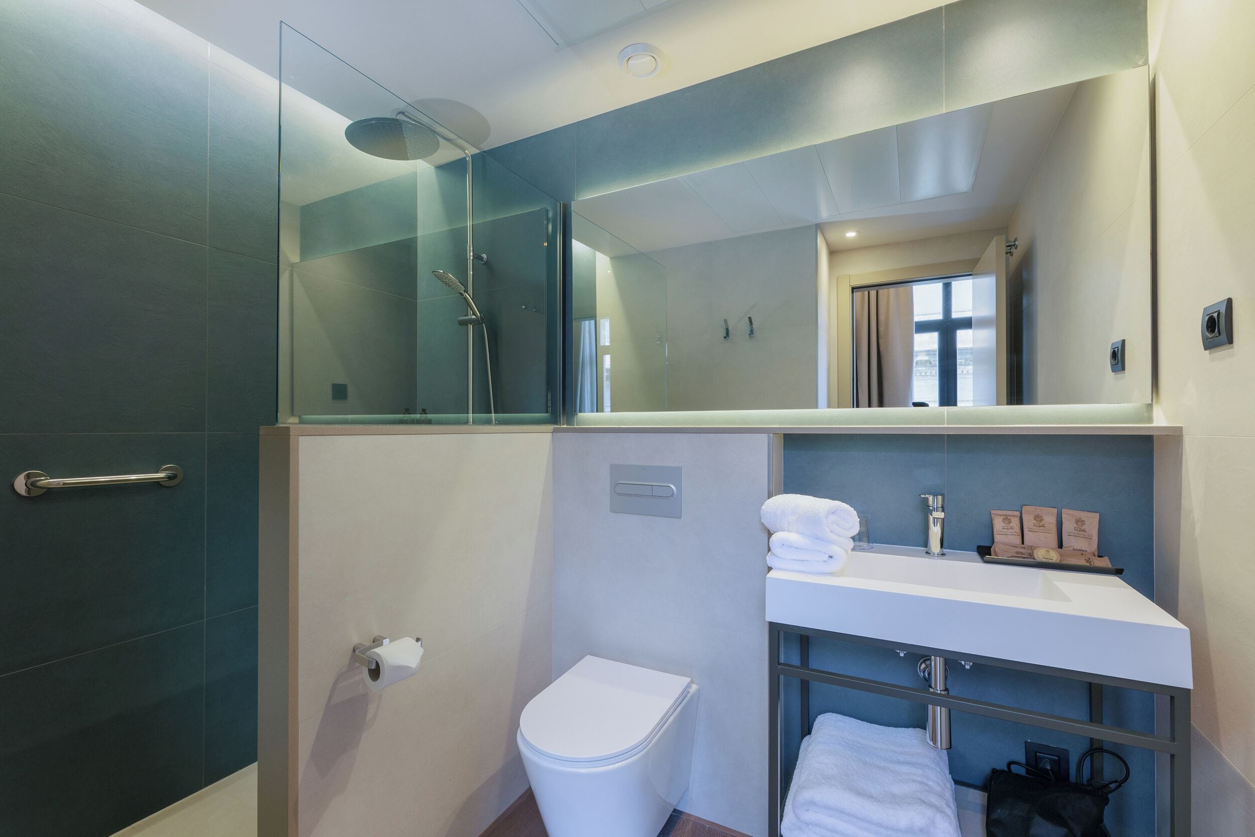 A modern bathroom with a glass shower enclosure, a white toilet, and a vanity with a mirror.