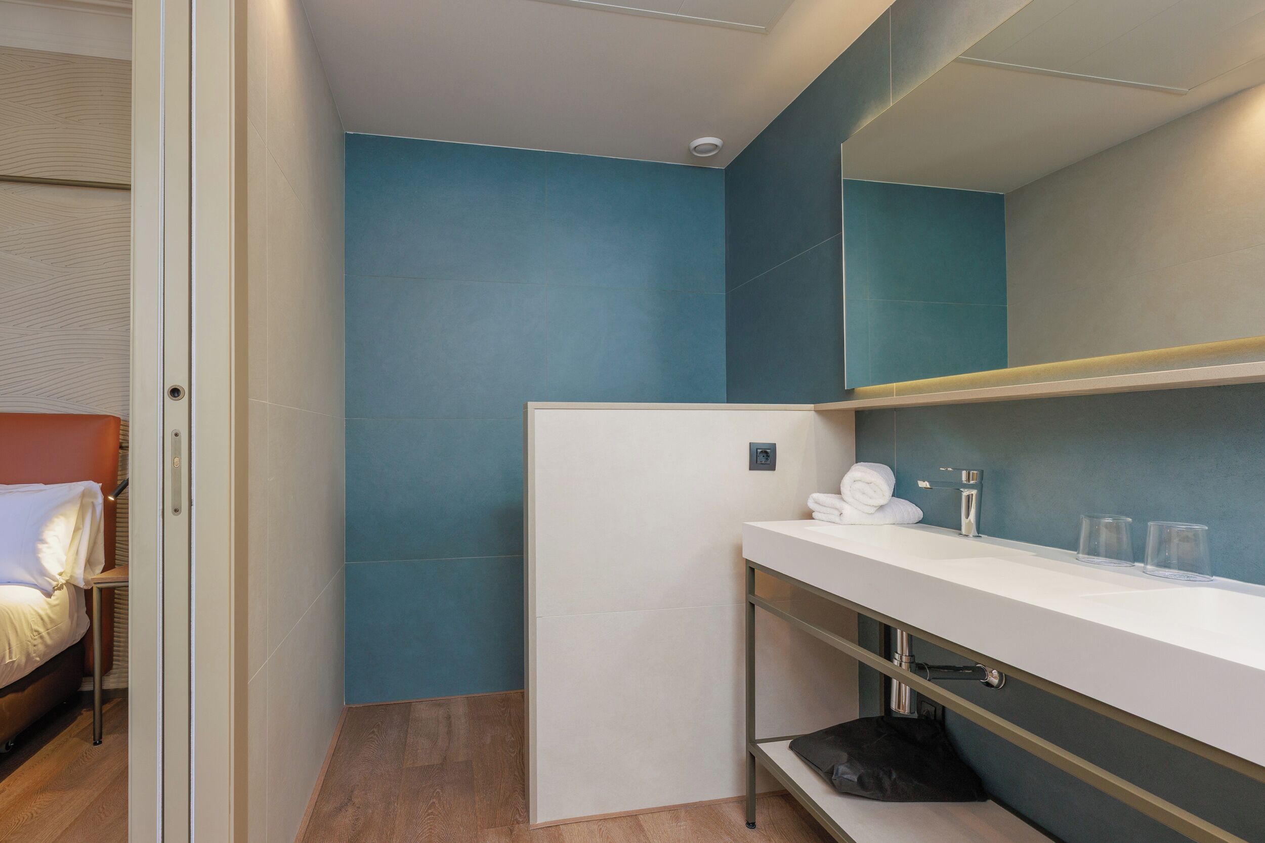 A modern bathroom with a white sink, a mirror, and a towel rack.